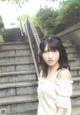 A woman in a white dress standing in front of some stairs.