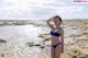 A woman in a blue bikini standing in the water.