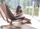 A woman sitting in a brown chair on a wooden floor.