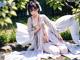 A woman in a white kimono sitting on the ground.