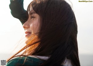 A woman with long brown hair and a green sweater.